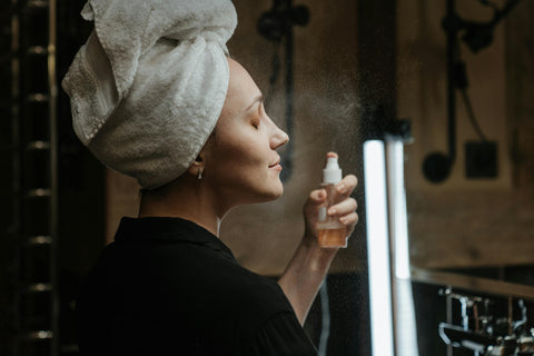 A woman using perfume on her face