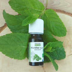 A bottle of Peppermint essential oil laying on top of Peppermint leafs