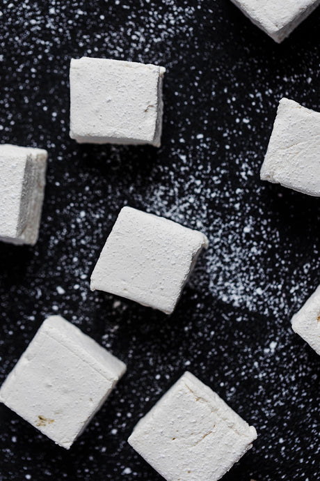 handcrafted marshmallows on black background with powdered sugar 