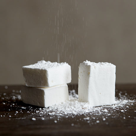 handcrafted marshmallows being dusted with powdered sugar