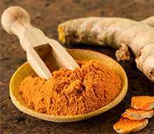 Pure raw and powdered Turmeric in a wooden bowl
