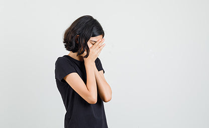 A stressed and upset woman putting her hands on her face
