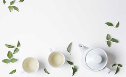 Background with two white tea cups, leaves and a white teapot