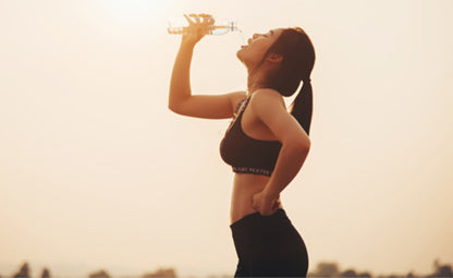 A woman drinking water after exercising or running