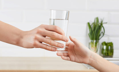 Hand passing glass of water to another