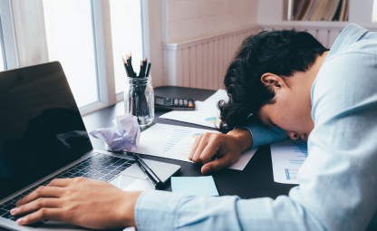 A person sleeping or feeling tired while working in front of the laptop