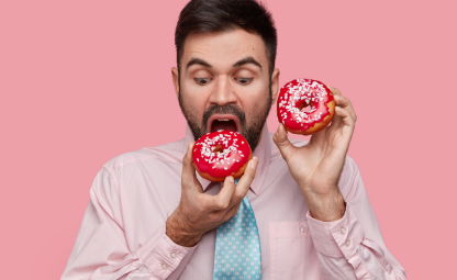 A person eating donuts and has a donut in hand