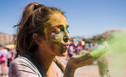 A woman blowing Holi colour from her hands