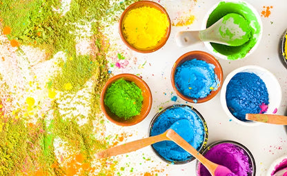 Different Holi colours in different bowls with spoons