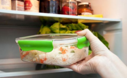 A hand putting sealed air tight container with rice in it into fridge