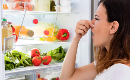 A person holding their nose due to rotten food in fridge