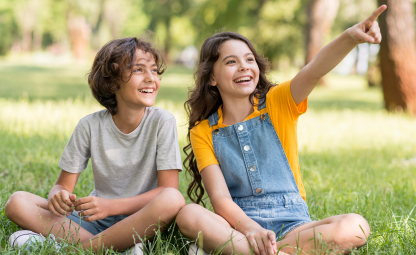 Two kids pointing at something and laughing