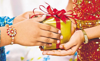A person giving Rakhi a gift with a red ribbon to his sister