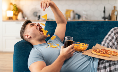 A person eating chips and lying down