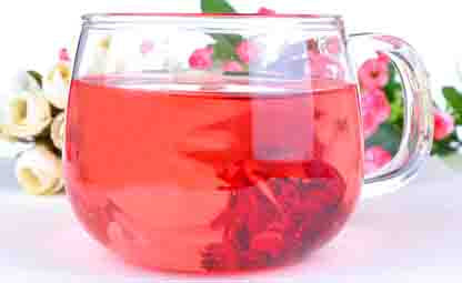 Hibiscus Tea in a glass mug and roses in the behind