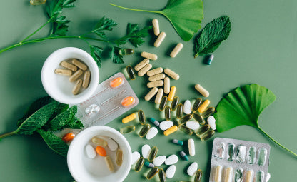 Medicines and capsules spread over a green table with leaves
