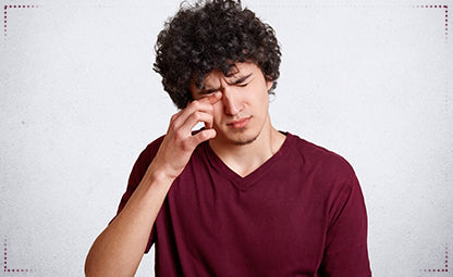 A man rubbing his eyes due to pain and irritation