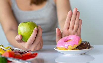 Saying no to sweet and sugary food (doughnut) and holding a green apple in hand