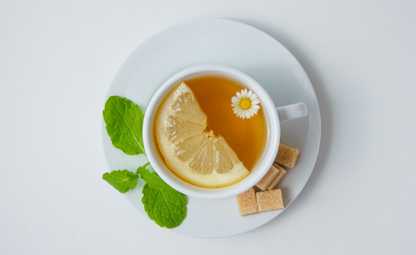 Curcumin tea in a white cup with sliced lime and chamomile