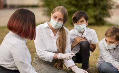 A woman teaching young kids to sanitise with sanitiser