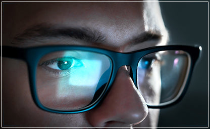 A man wearing eyeglasses with a computer reflection on his glassed