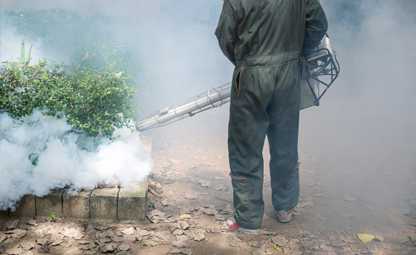 A person using mosquito blowing machine in a park
