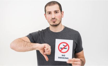 A man holding no smoking and giving it a thumbs down