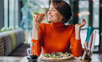 A woman eating pizza at a restaurant
