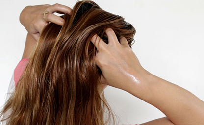 A person massaging their hair with oil