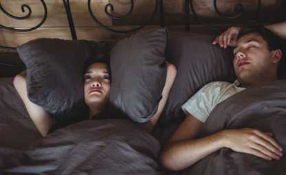 A woman being disturbed due to snoring from her partner