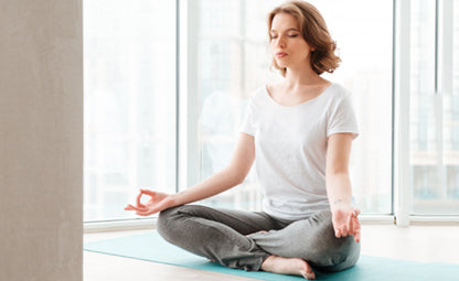 A woman doing meditation or yoga on a mat