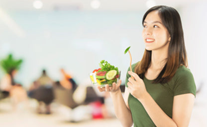 A happy woman having a bowl of fresh vegetables and salad