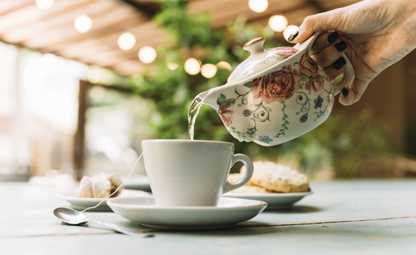 Pouring herbal tea from a white pot into a cup