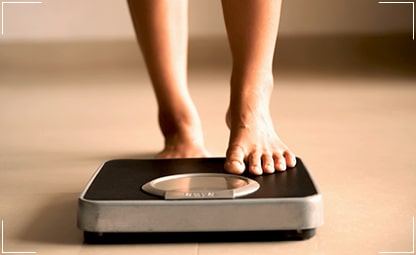 A person checking their body weight in a weighing machine