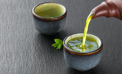 Pouring green tea from a teapot into a cup