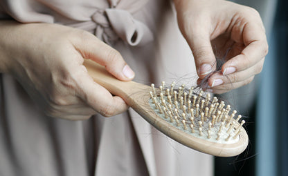 A woman pulling tangled hair from a brush