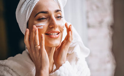 A woman doing a skincare routine and applying cream on her face