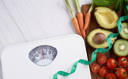 Weighing machine with measuring tape and fresh tomatoes, avocados, kiwis and carrots