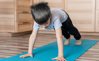 A kid doing exercise on the blue mat