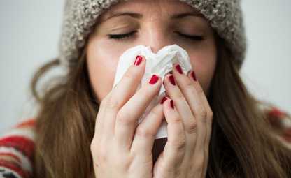 A woman having a cold and sneezing in winter