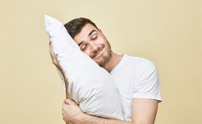 A person holding a pillow with their eyes closed