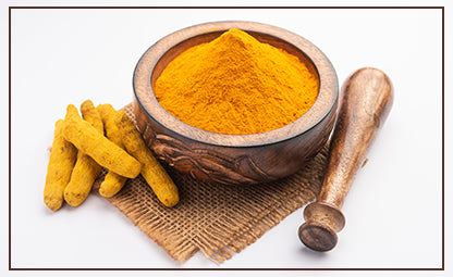 Pure Curcumin powder in a wooden pestle and mortar next to organic curcumin on a jute rug