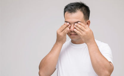 A person rubbing his eyes due to a vision problem