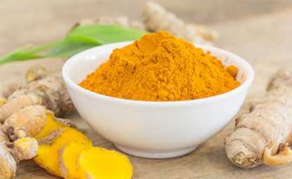 Bright yellow Curcumin in a white bowl and raw sliced cut curcumin around it