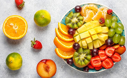 Finely sliced healthy fruits on a plate like mango, kiwi, oranges, grapes and strawberries