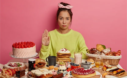 A woman stopping from eating sugary foods and sweets