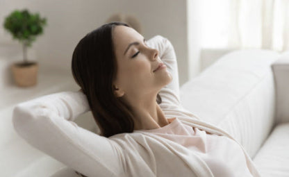 A woman relaxing and stress-free sitting on the couch with closed eyes
