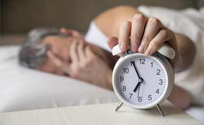 A man having difficulty waking up and putting the alarm clock off