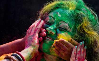 A person celebrating the Holi festival with colours beings applied to their face