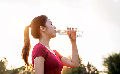 A woman drinking water from a plastic bottle after a morning walk